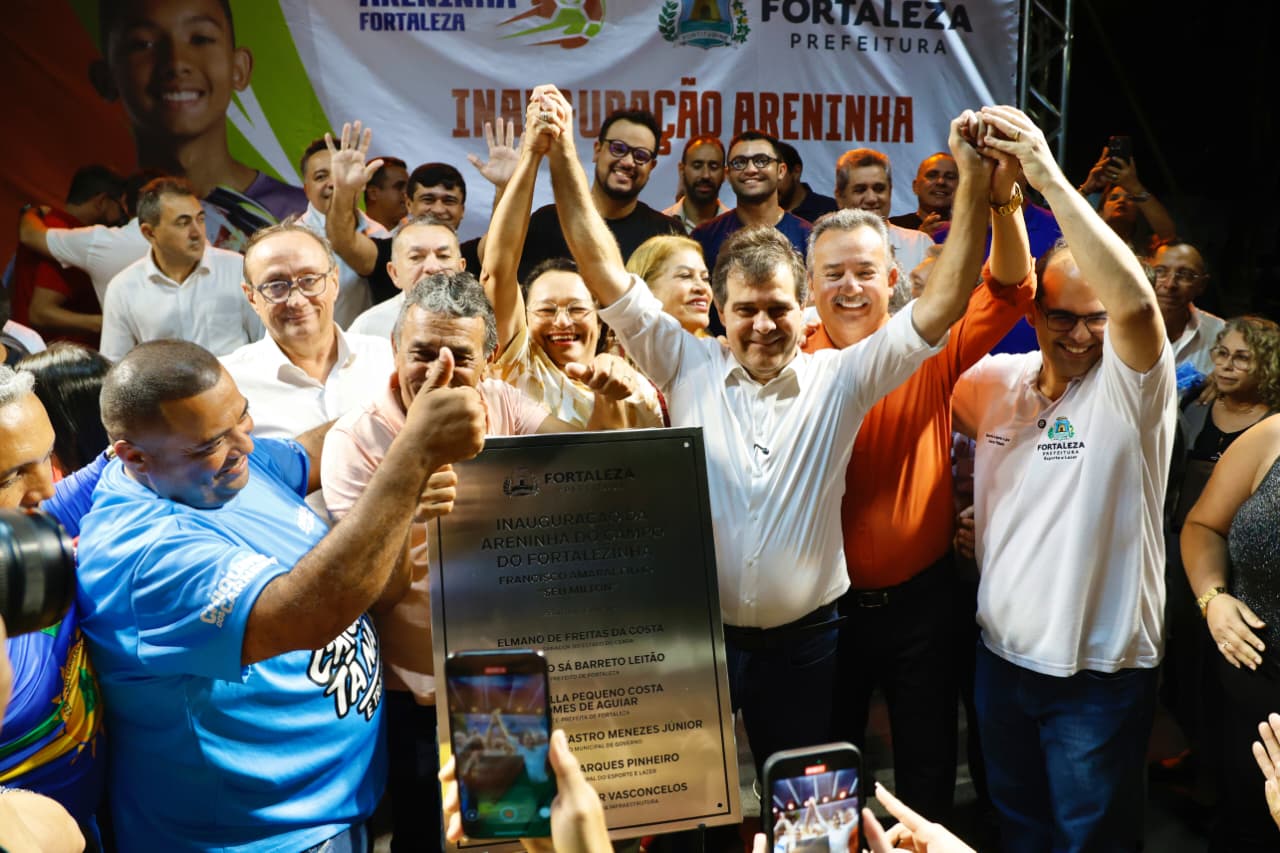 grupo de pessoas em um palco com uma placa de inauguração